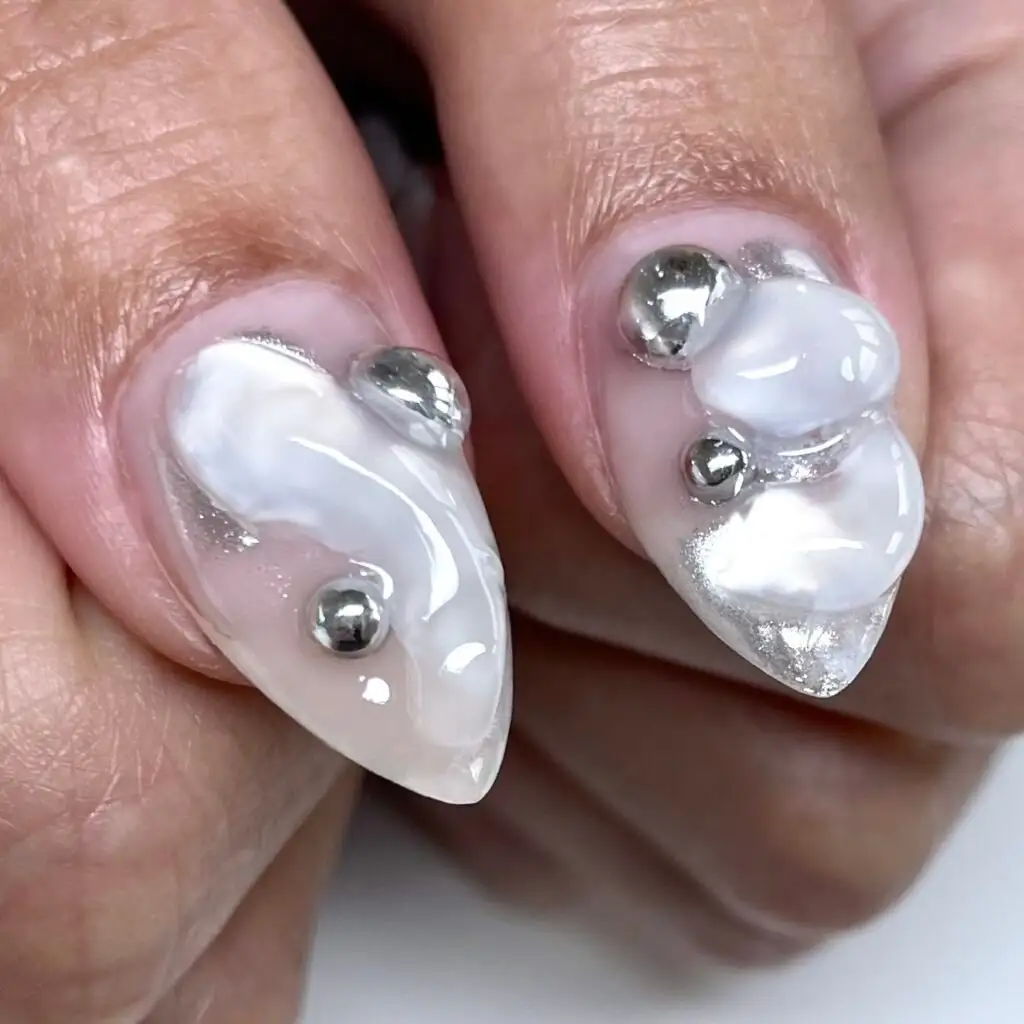Milky white nails with sculpted 3D shapes and silver pearls